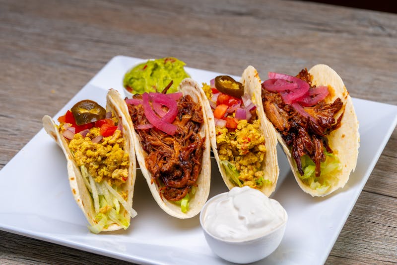 Sweet pork tacos in flour tortillas with colorful toppings